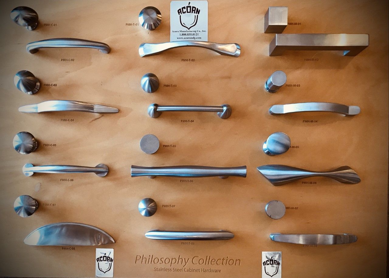 Display of various metal cabinet handles and knobs mounted on a wooden board.
