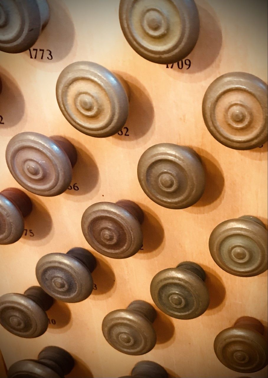 Rows of circular, wooden organ stops, various shades of brown, on a light-colored wooden panel.