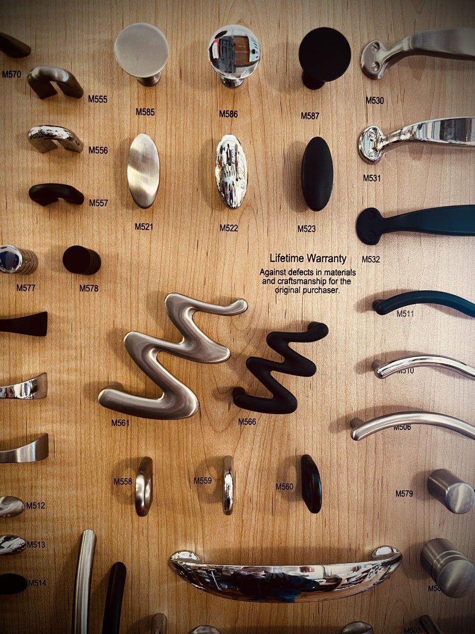 Cabinet hardware samples mounted on a wooden board.