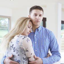 A man and a woman are hugging each other in a living room.