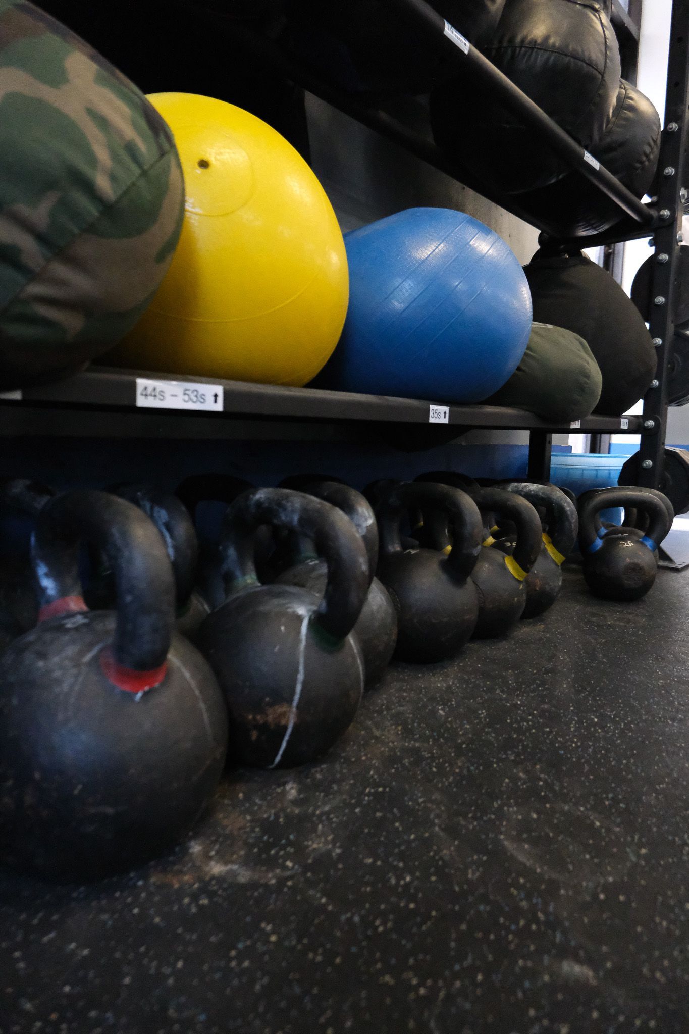 A bunch of kettlebells are lined up on a shelf in a gym