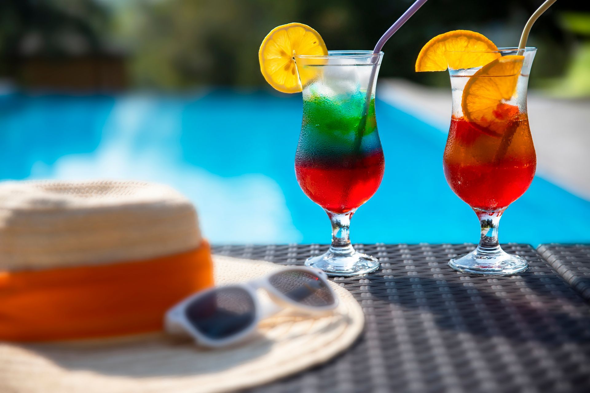 All Inclusive Two drinks are sitting on a table next to a hat and sunglasses.