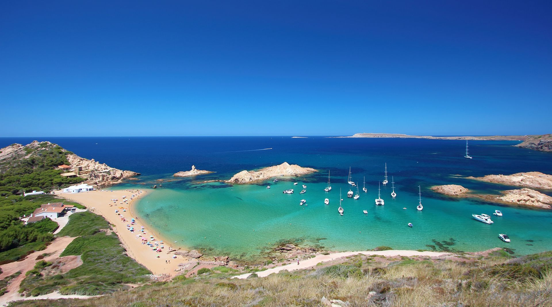 Menorca An aerial view of a beach with boats in the water.