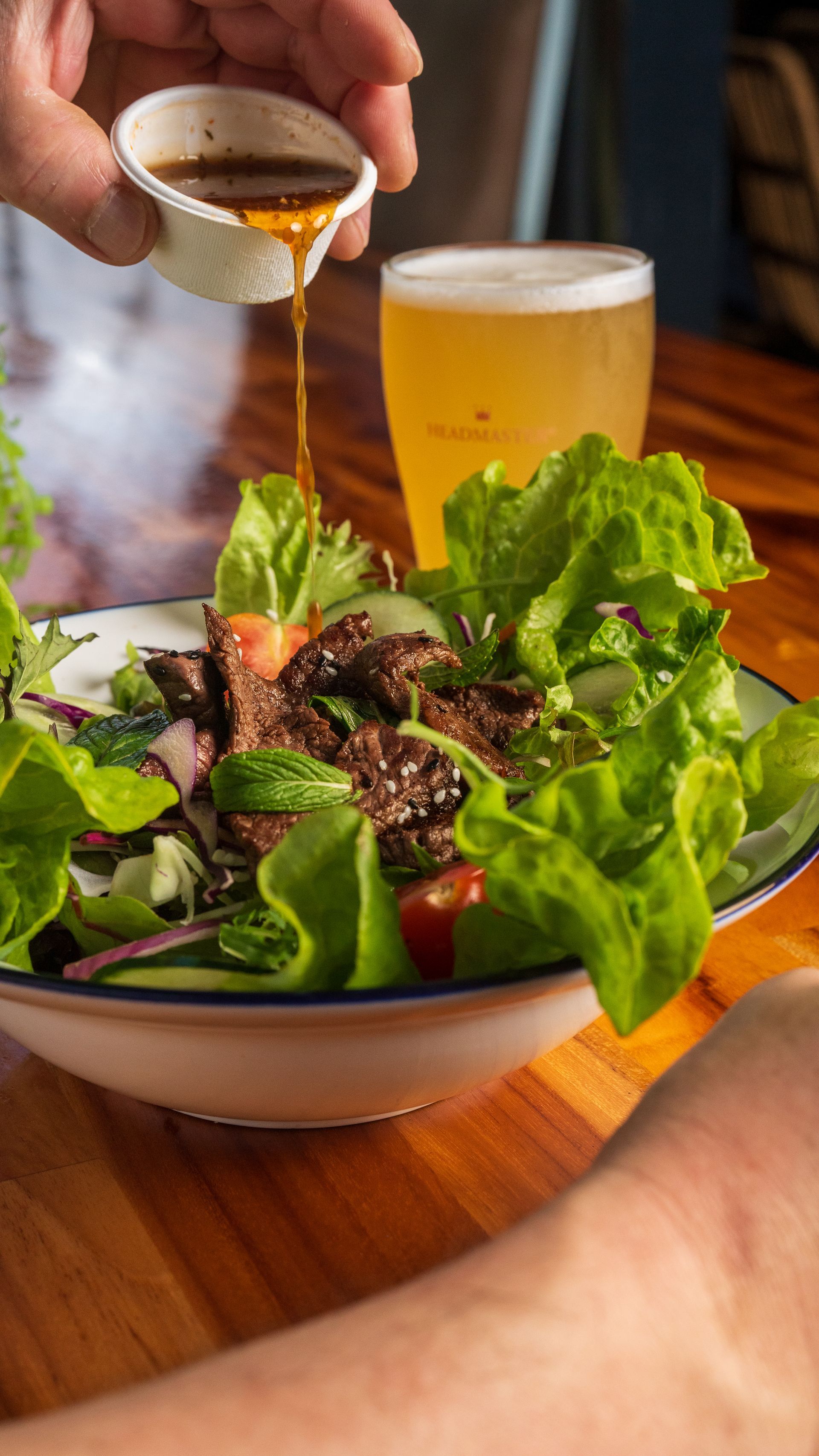 A Person is Pouring Sauce on a Salad — Chop 'n Chill South West Rocks in South West Rocks, NSW