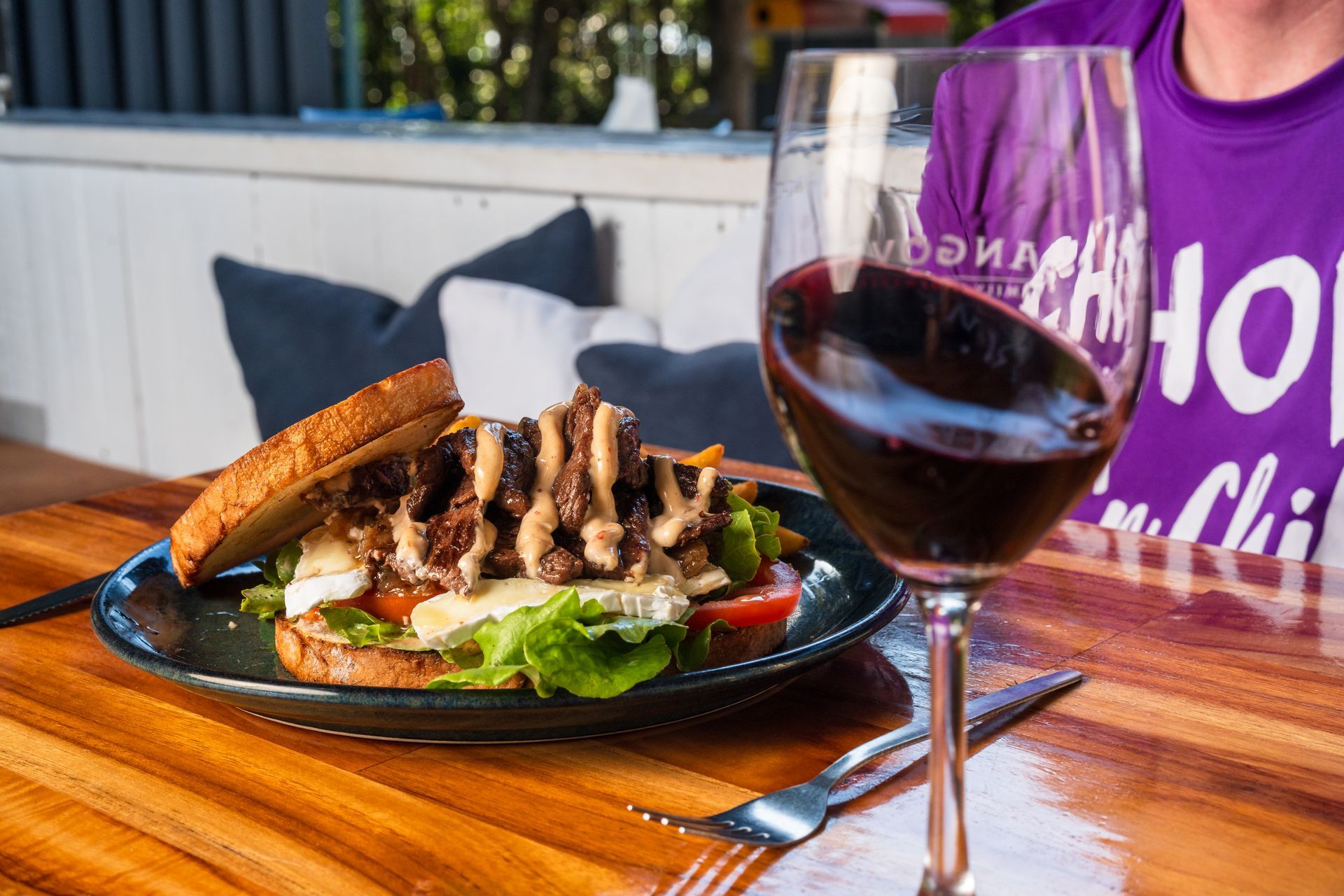 A Sandwich and a Glass of Wine Are on a Wooden Table — Chop 'n Chill South West Rocks in South West Rocks, NSW
