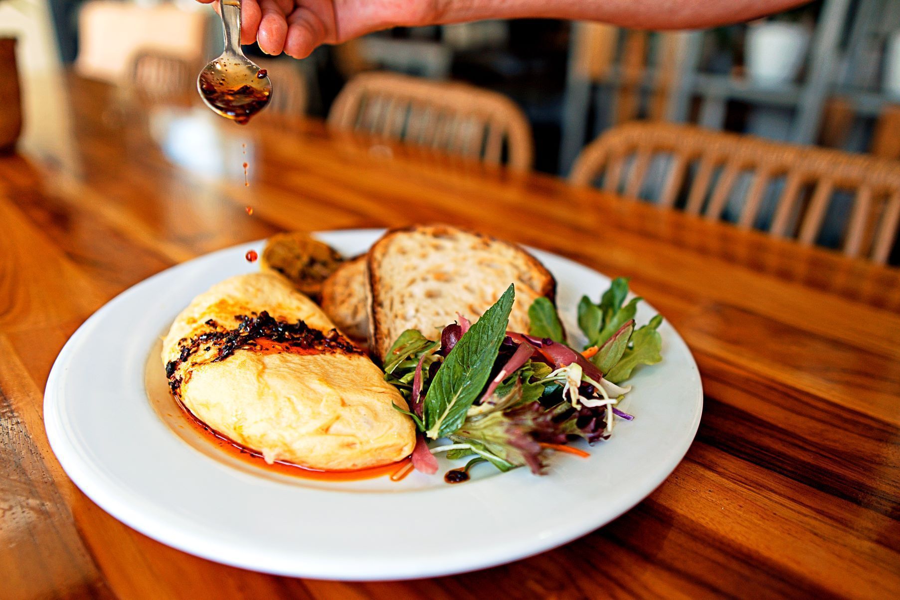 A Person is Pouring Syrup on a Plate of Food on a Wooden Table — Chop 'n Chill South West Rocks in South West Rocks, NSW