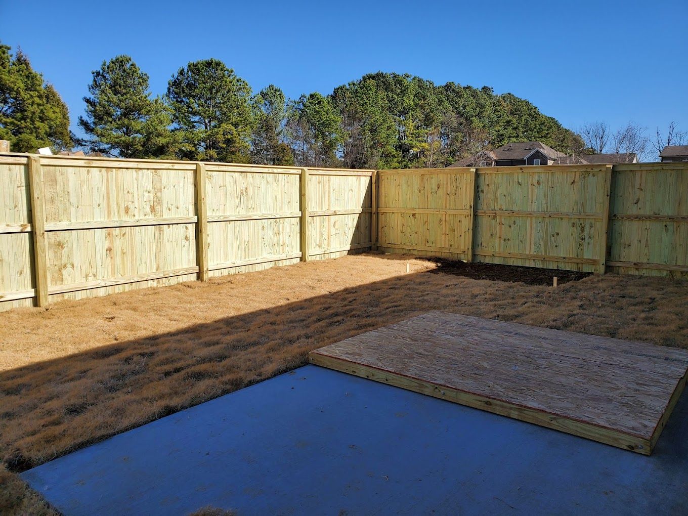 A chain link fence is surrounded by a wooden fence in a backyard.
