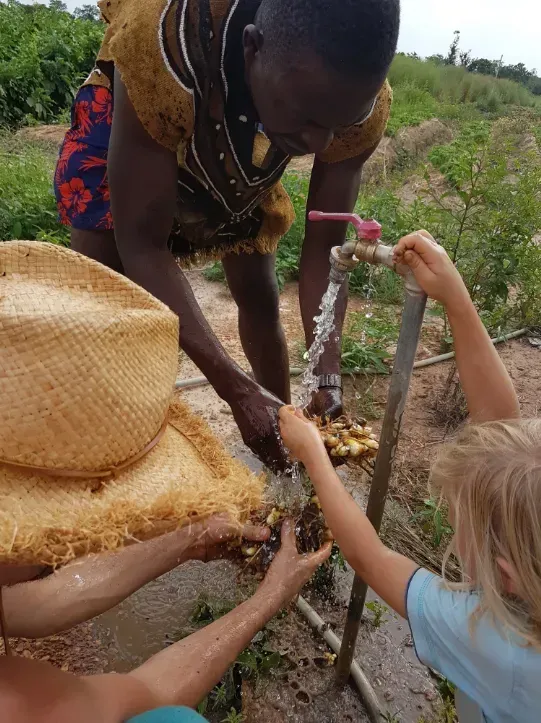 Un homme verse de l'eau dans la main d'un enfant