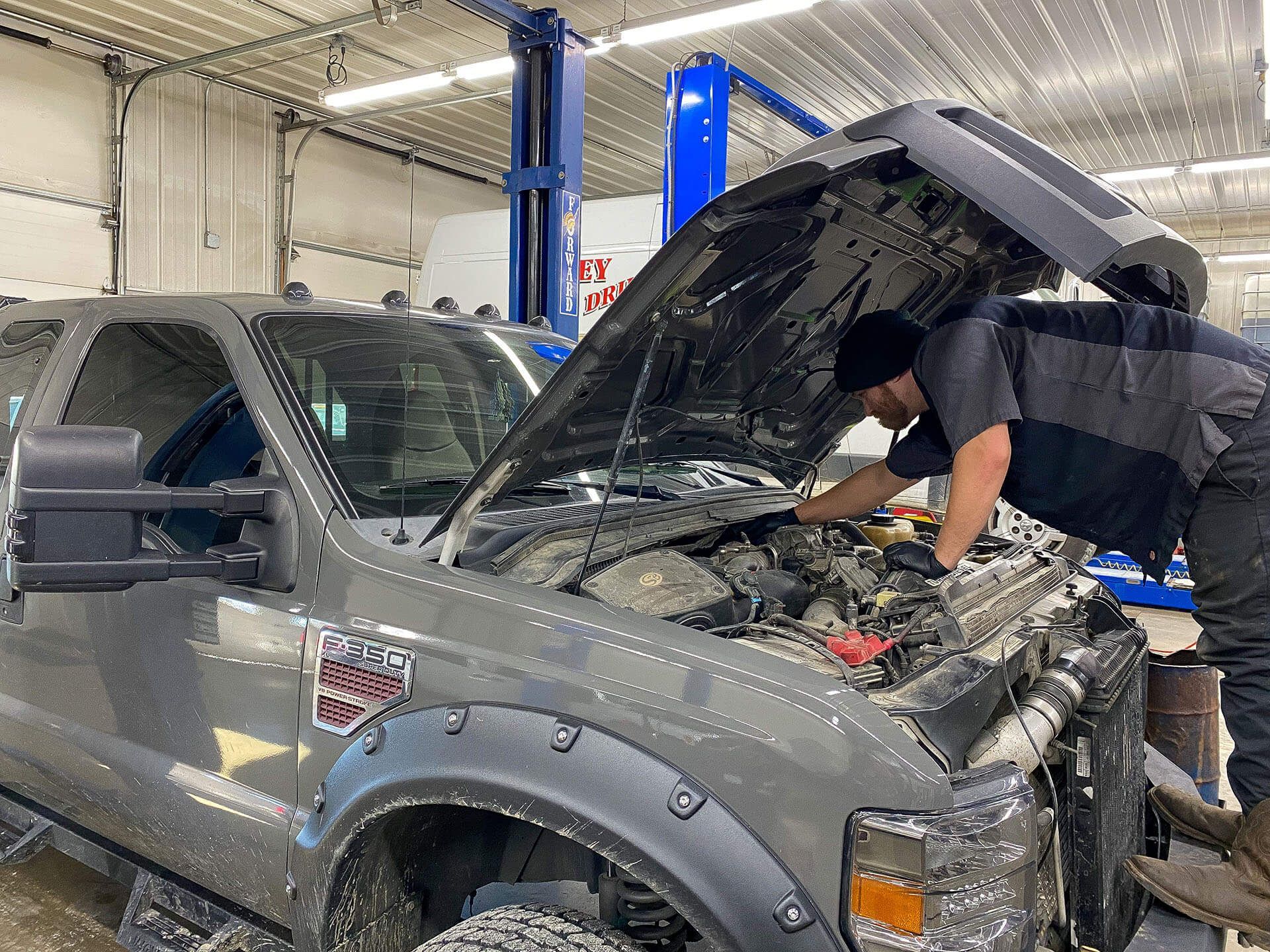 Technician Working on the Engine Bay of a Gray Ford F-250 Pickup Truck | Elite Truck & Auto Repair