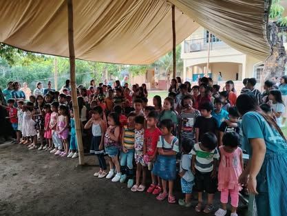 A large group of children are standing under a tent.