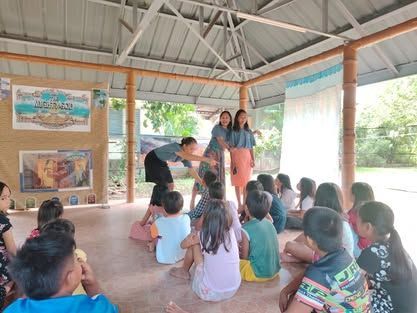 A group of children are sitting on the floor in a room under a canopy.