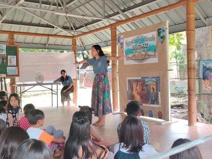 A woman is standing in front of a group of children.