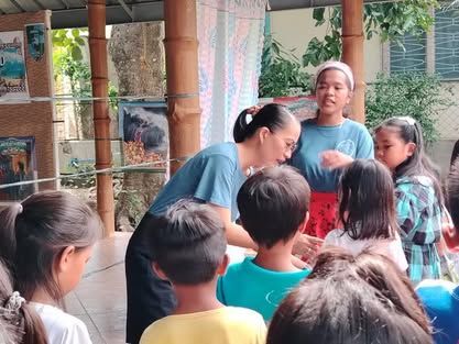 A woman is talking to a group of children.