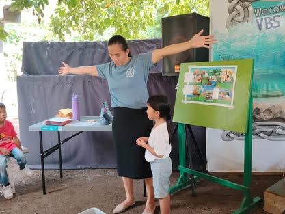 A woman is standing next to a child in front of a green easel.