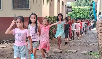 A group of young girls are walking down a dirt road.