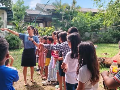 A woman is standing in front of a group of children.