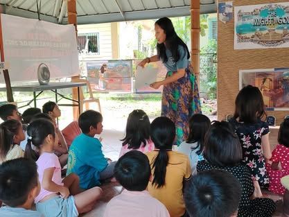 A woman is giving a presentation to a group of children.