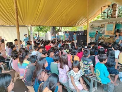 A large group of people are sitting under a tent.