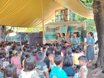 A large group of people are sitting under a tent.
