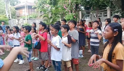 A group of children are standing in a line outside.
