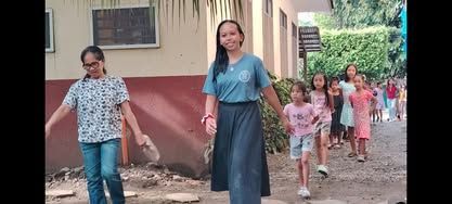 A group of people are walking down a dirt road holding hands.