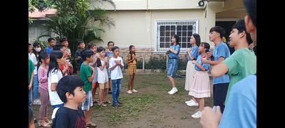 A group of children are standing in a circle in front of a house.