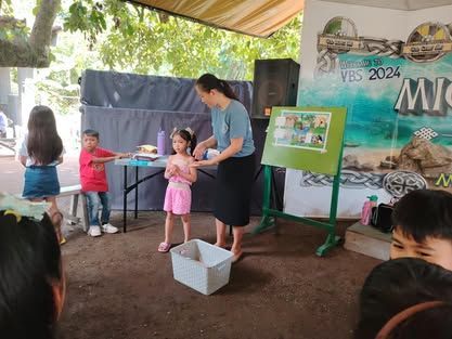 A woman is standing in front of a group of children.