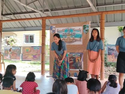 Two women are standing in front of a group of children.