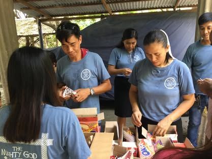 A group of people are standing around a table with boxes of food.