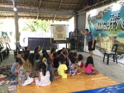 A group of children are sitting on the floor listening to a presentation.