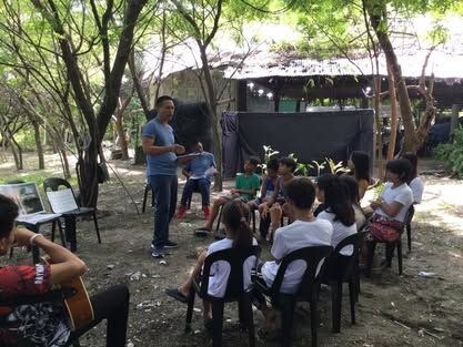 A man is standing in front of a group of people sitting in chairs.