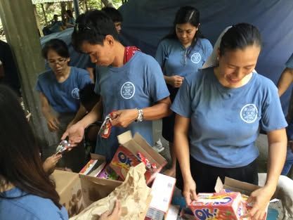 A group of people in blue shirts are standing around a table.
