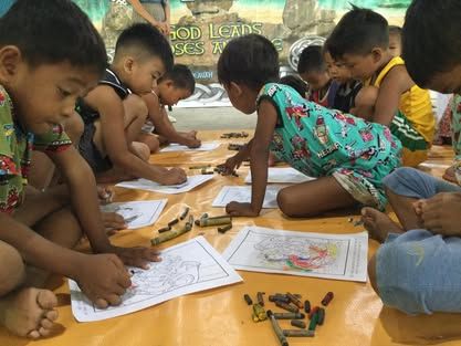 A group of children are sitting on the floor drawing with crayons.
