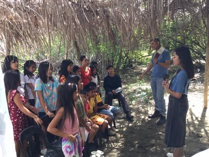 A group of people are sitting under a thatched roof.