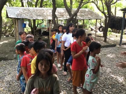 A group of children are standing in a line outside.