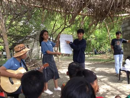 A man is playing a guitar in front of a group of people.
