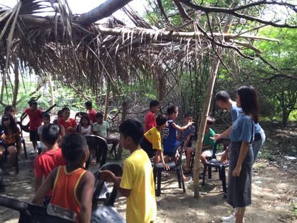 A group of people are sitting under a thatched roof.