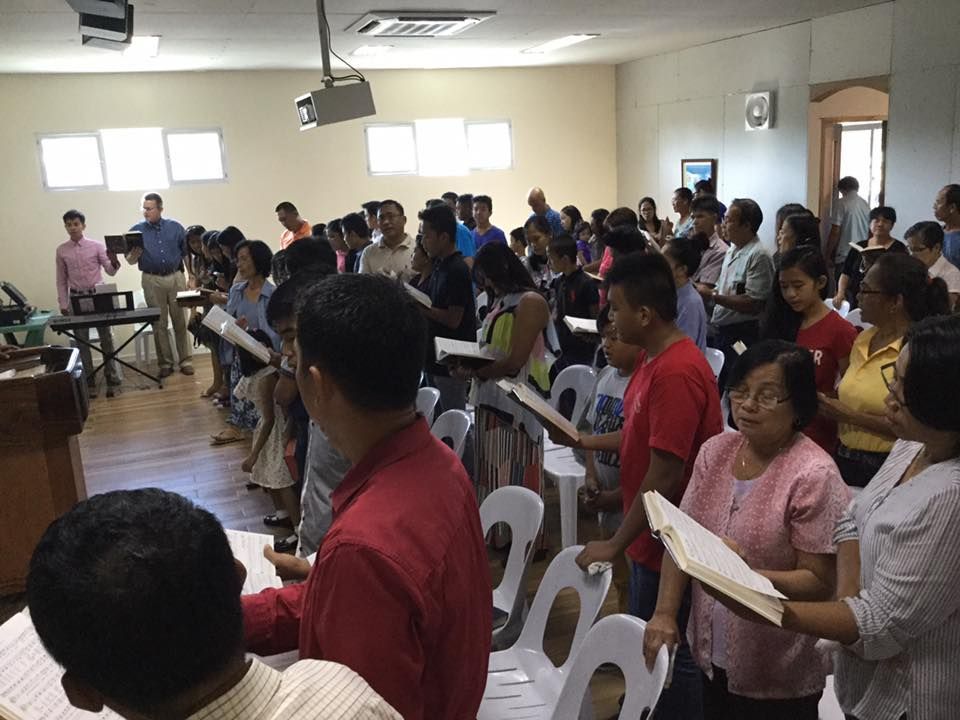 A large group of people are singing in a room.