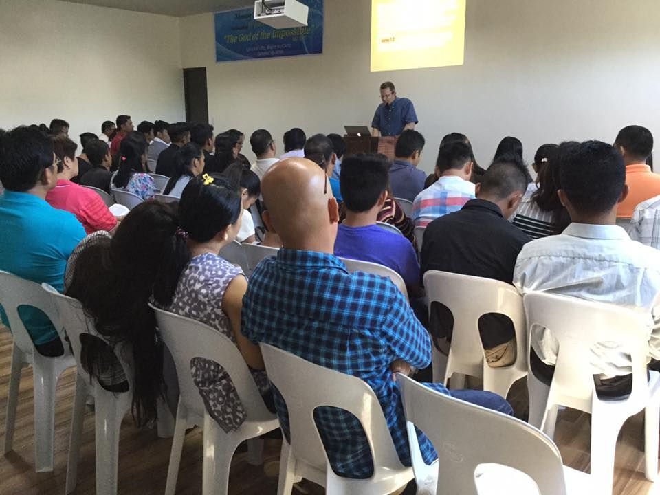 A man is giving a presentation to a group of people sitting in chairs.
