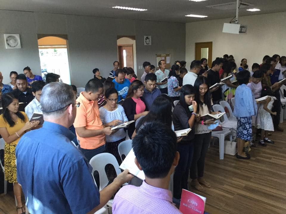 A large group of people are singing in a church.