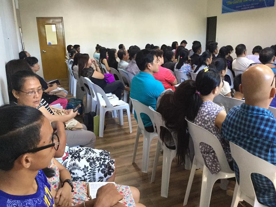 A large group of people are sitting in chairs in a room.