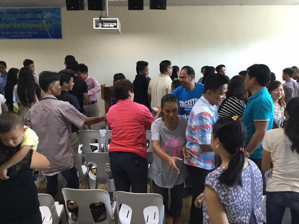 A group of people are dancing in a room with a sign that says ' jesus ' on it