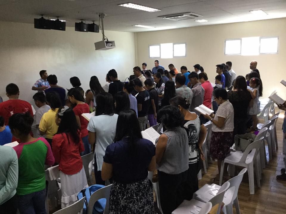 A large group of people are singing in a room.