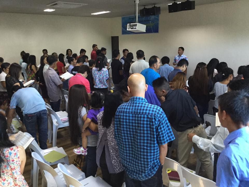A large group of people are gathered in a room with a projector on the ceiling