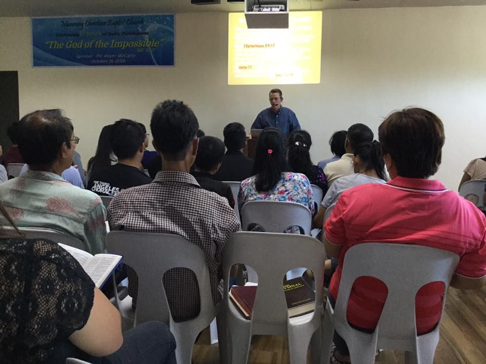 A group of people are sitting in chairs in front of a man giving a presentation.