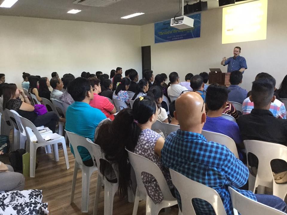 A man is giving a presentation to a large group of people sitting in chairs.