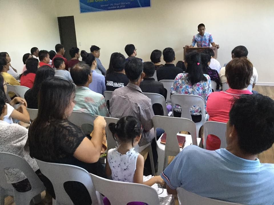 A group of people are sitting in chairs listening to a man at a podium