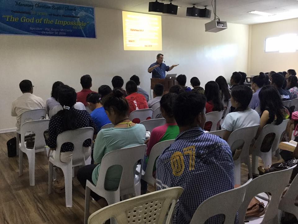 A man is giving a presentation to a group of people sitting in chairs.