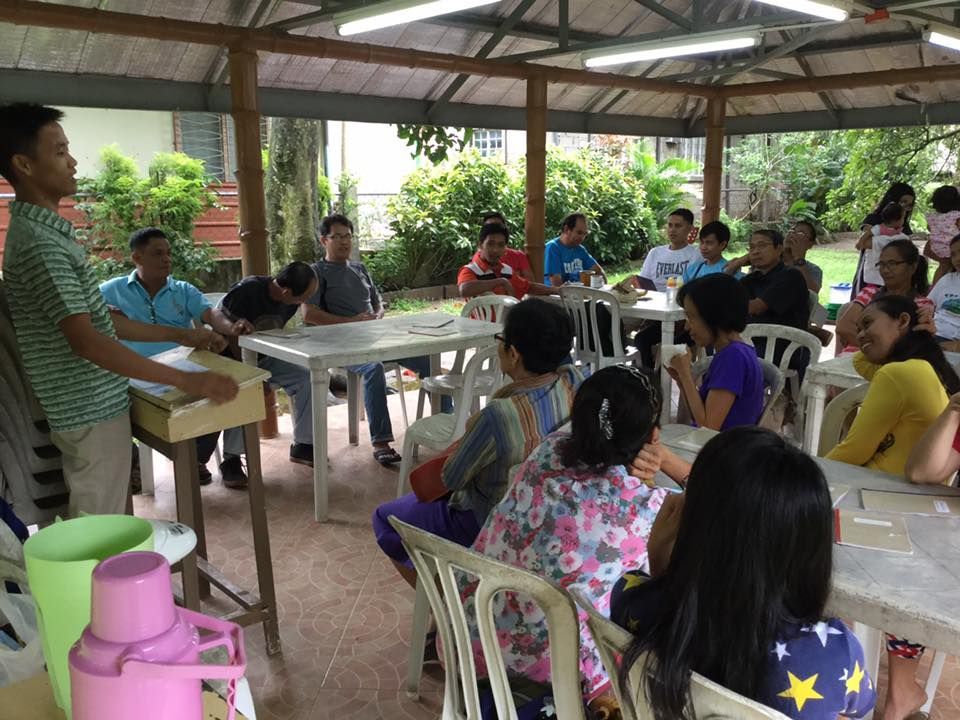 A man is giving a presentation to a group of people sitting at tables.