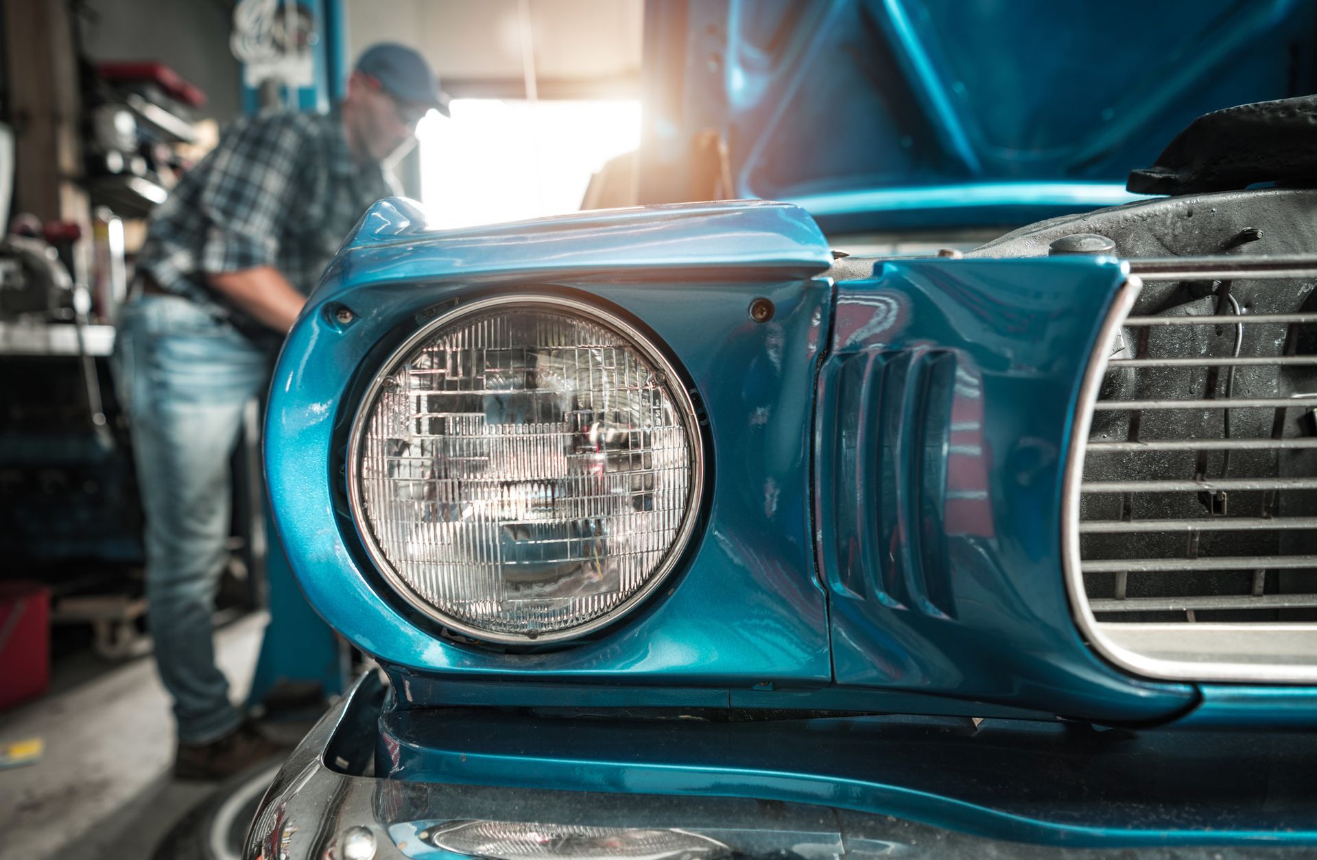 A man is working on a blue car in a garage.